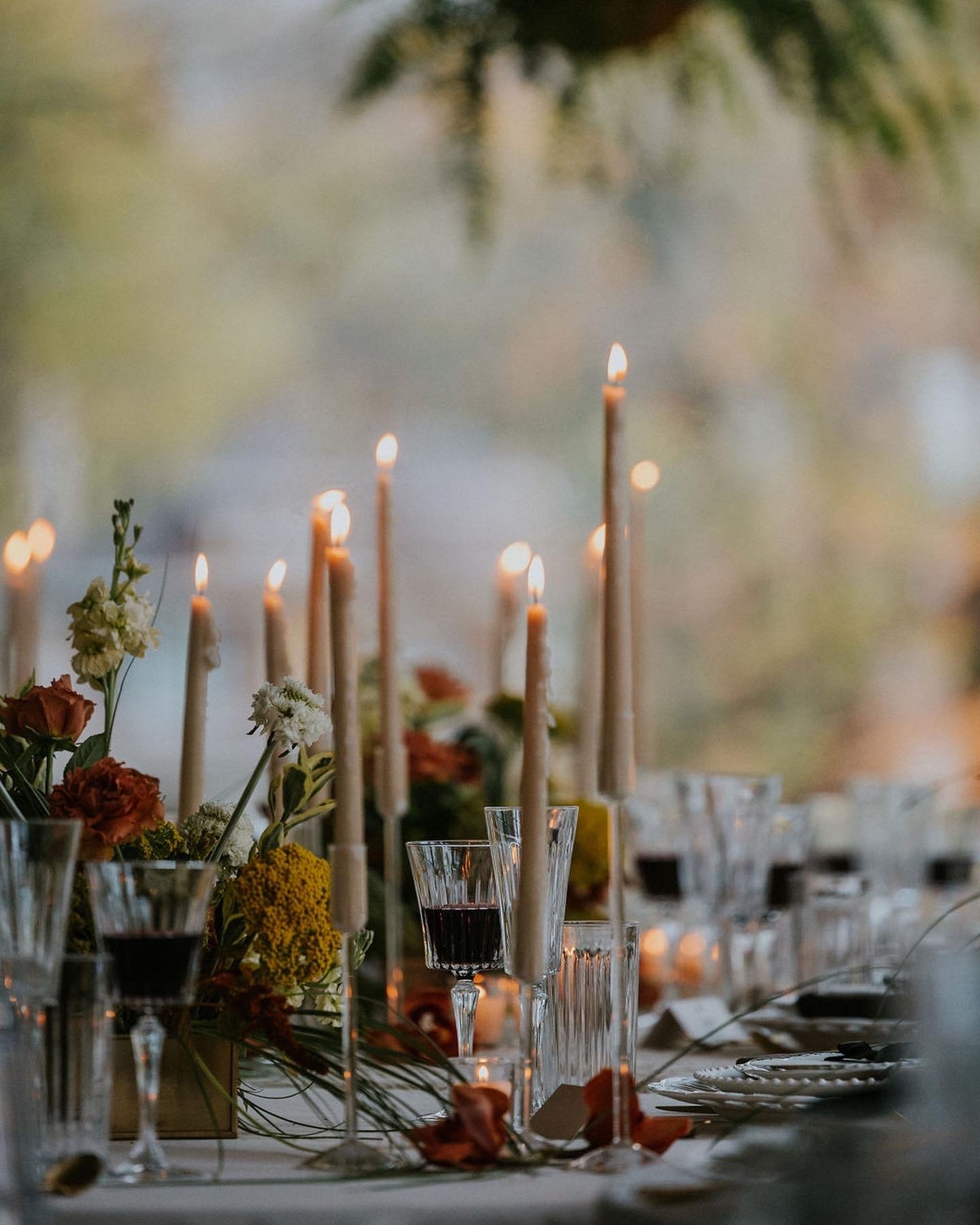 Taper candles and wine glasses amid autumn florals